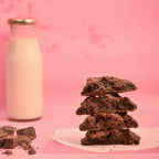 Stack of freshly baked Double chocolate chip cookies with visible melted chocolate and milk bottle in the background with pink background product photography