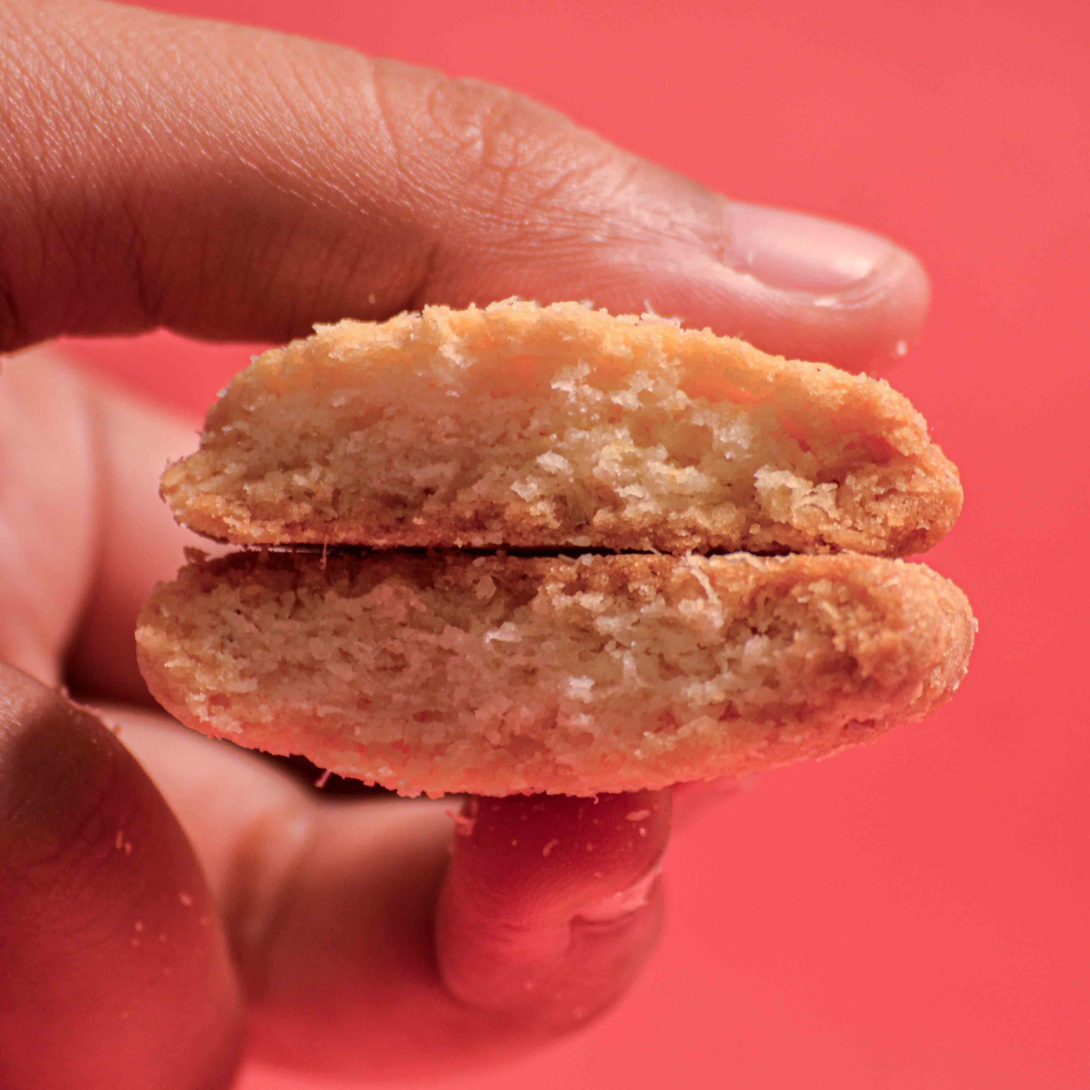 Coconut cookie broken in half showing the crunchy texture of the cookie professional food photography