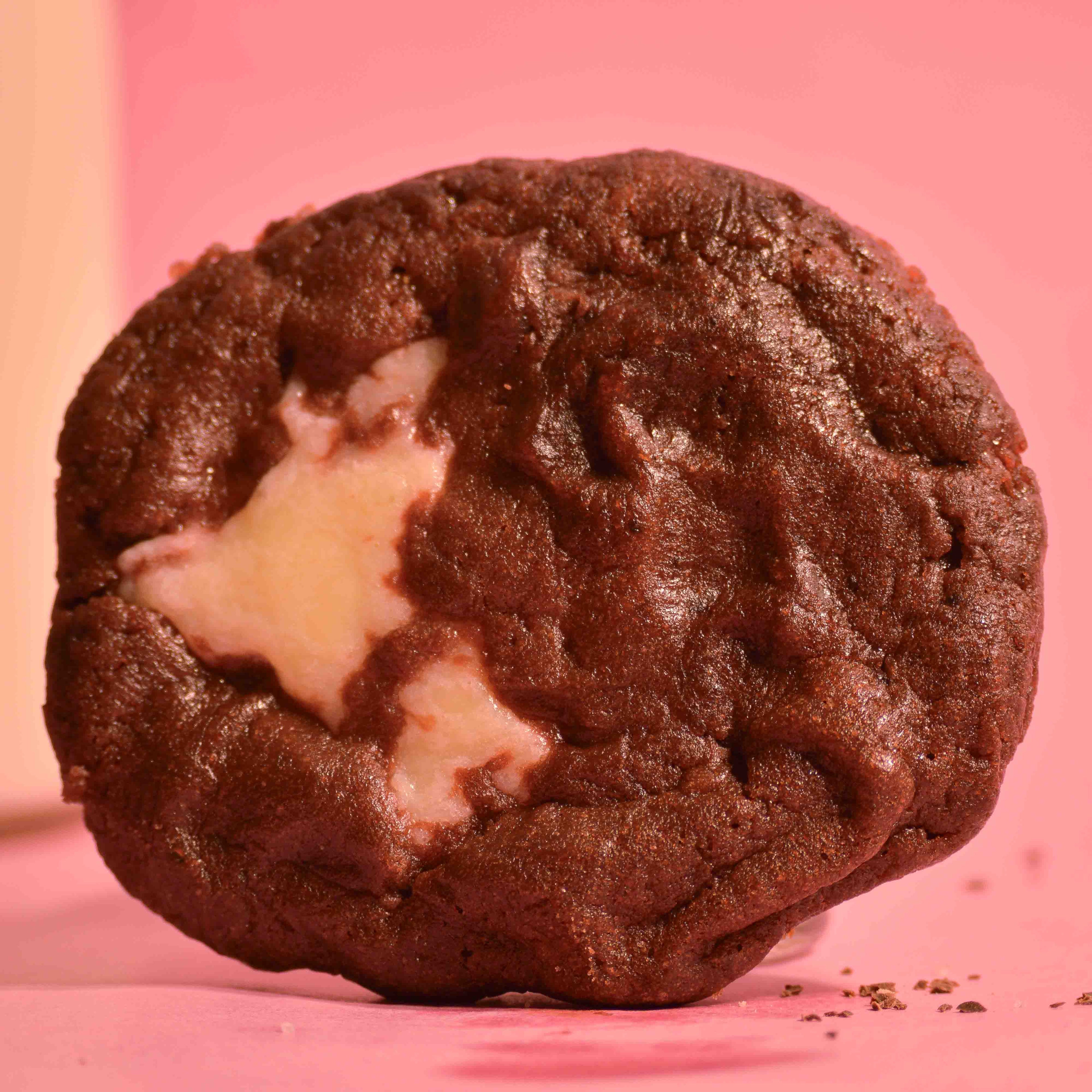 Red Velvet center filled cookie with filling oozing out, on a pink background photography.