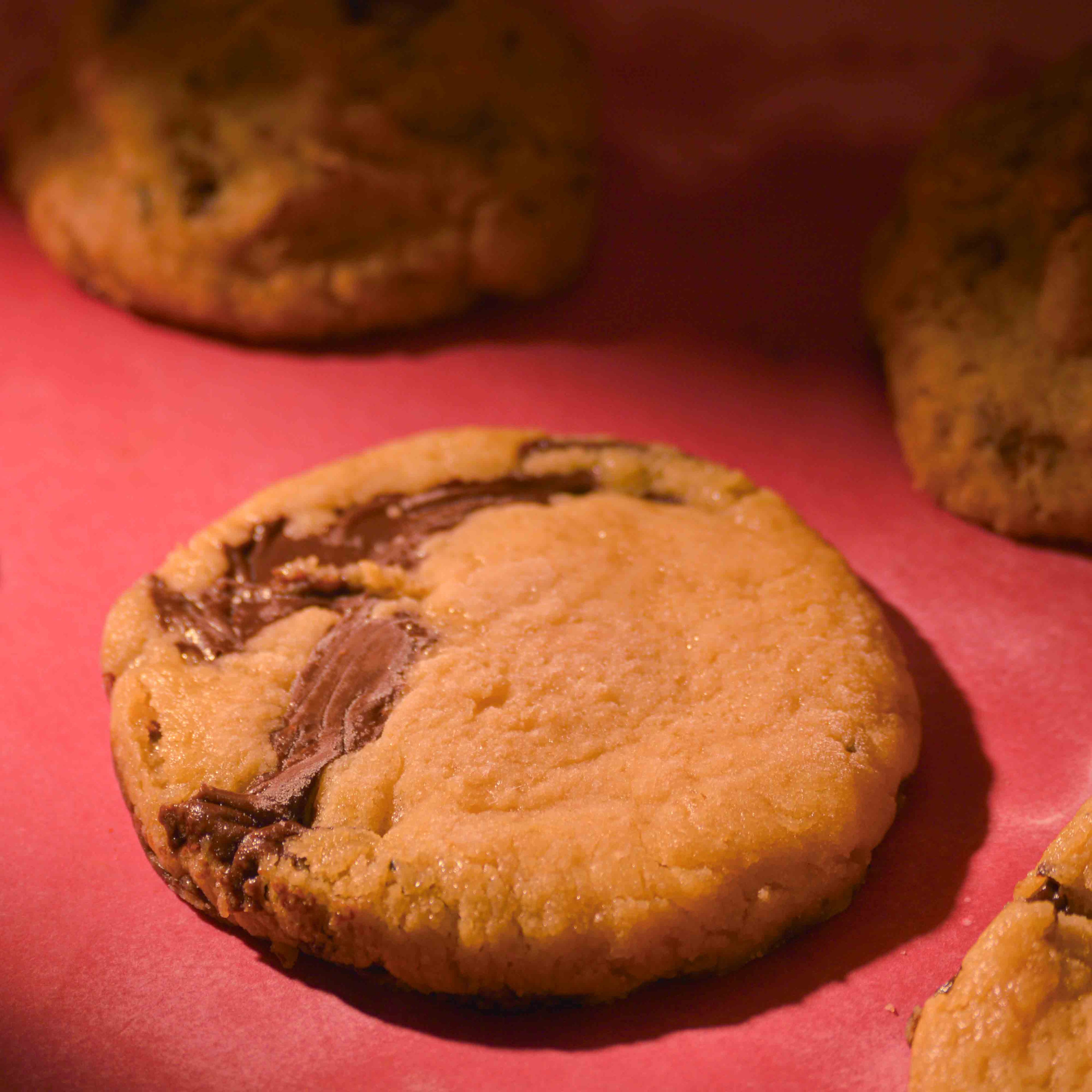Thick Chocolava chocolate filled cookies topped with sea salt gooey center and crispy edges on a pink background professional photography