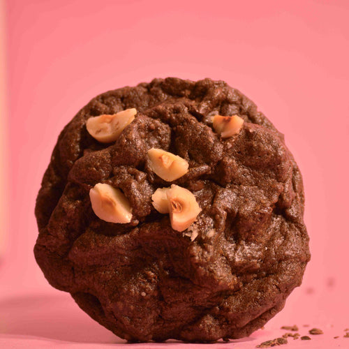 Soft baked double chocolate cookie with gooey center and crackled top with hazelnuts with a pink background photography