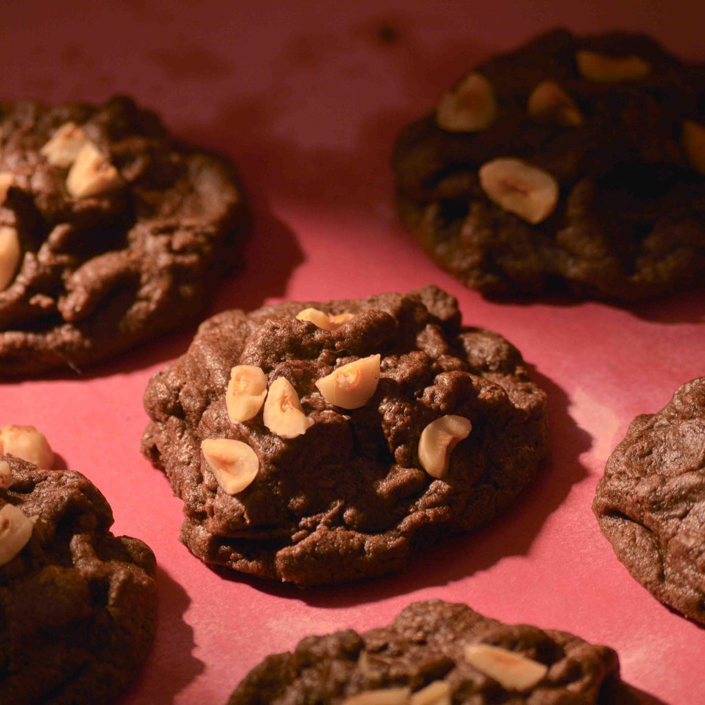 Thick hazelnut chocolate cookies topped with sea salt gooey center and crispy edges on a pink background professional photography
