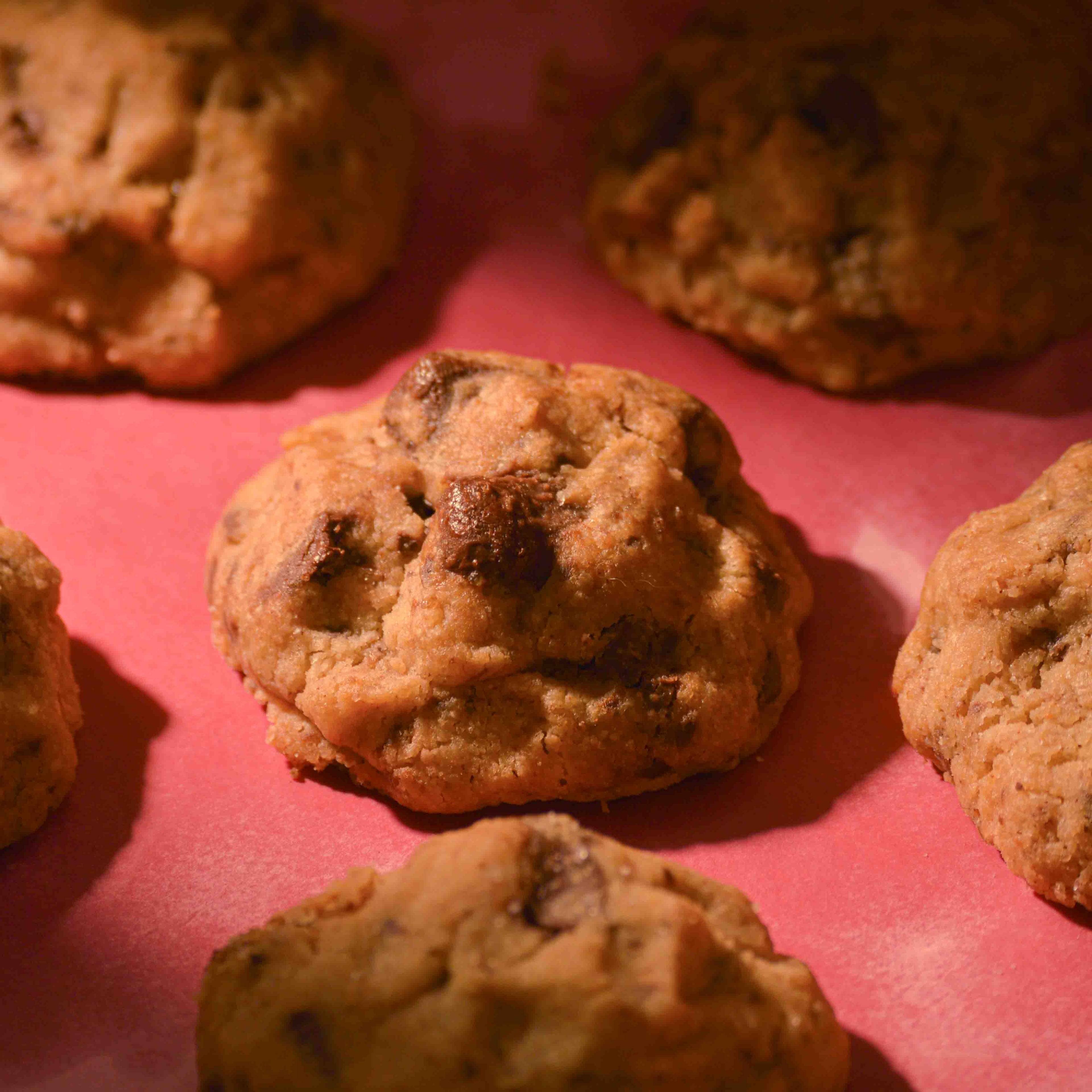 Thick Choco Chunk cookies topped with sea salt gooey center and crispy edges on a pink background professional photography